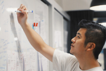 Man in office writing on a whiteboard.