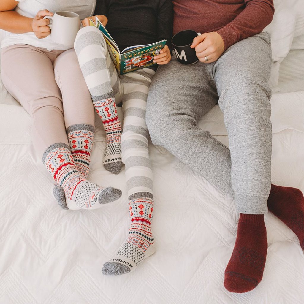 Three people wearing holiday socks