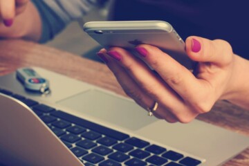 Woman-looking-at-phone-with-laptop