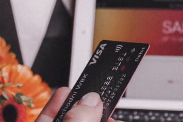 Person holding credit card in front of computer screen