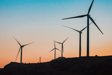 wind turbines in front of a sunset and hills