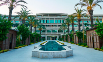 Palm tree-lined pathway leading up to the front of a large hotel.