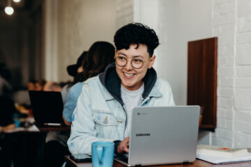 woman working at coffee shop with laptop at a table.