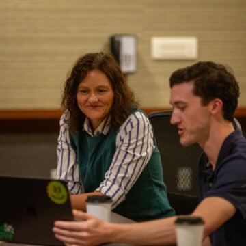 A man a woman sitting next to each other while looking at a laptop.